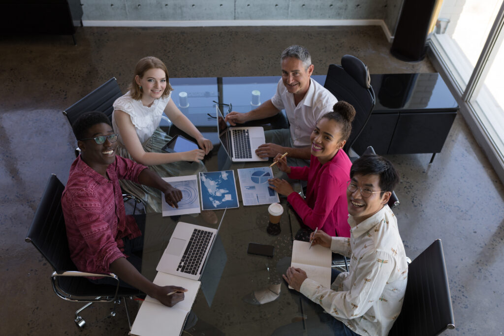 A diverse group of professionals smiling around a conference table.