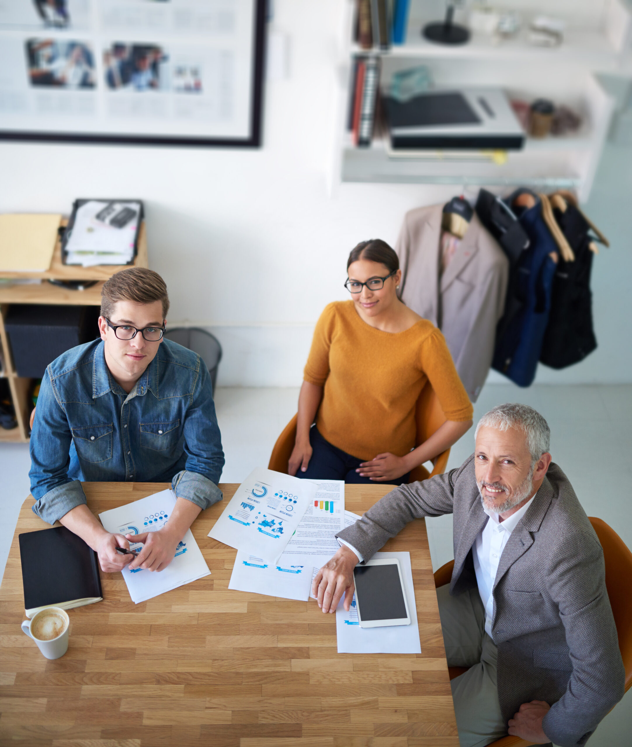 Three professionals in a meeting with charts and documents on the table